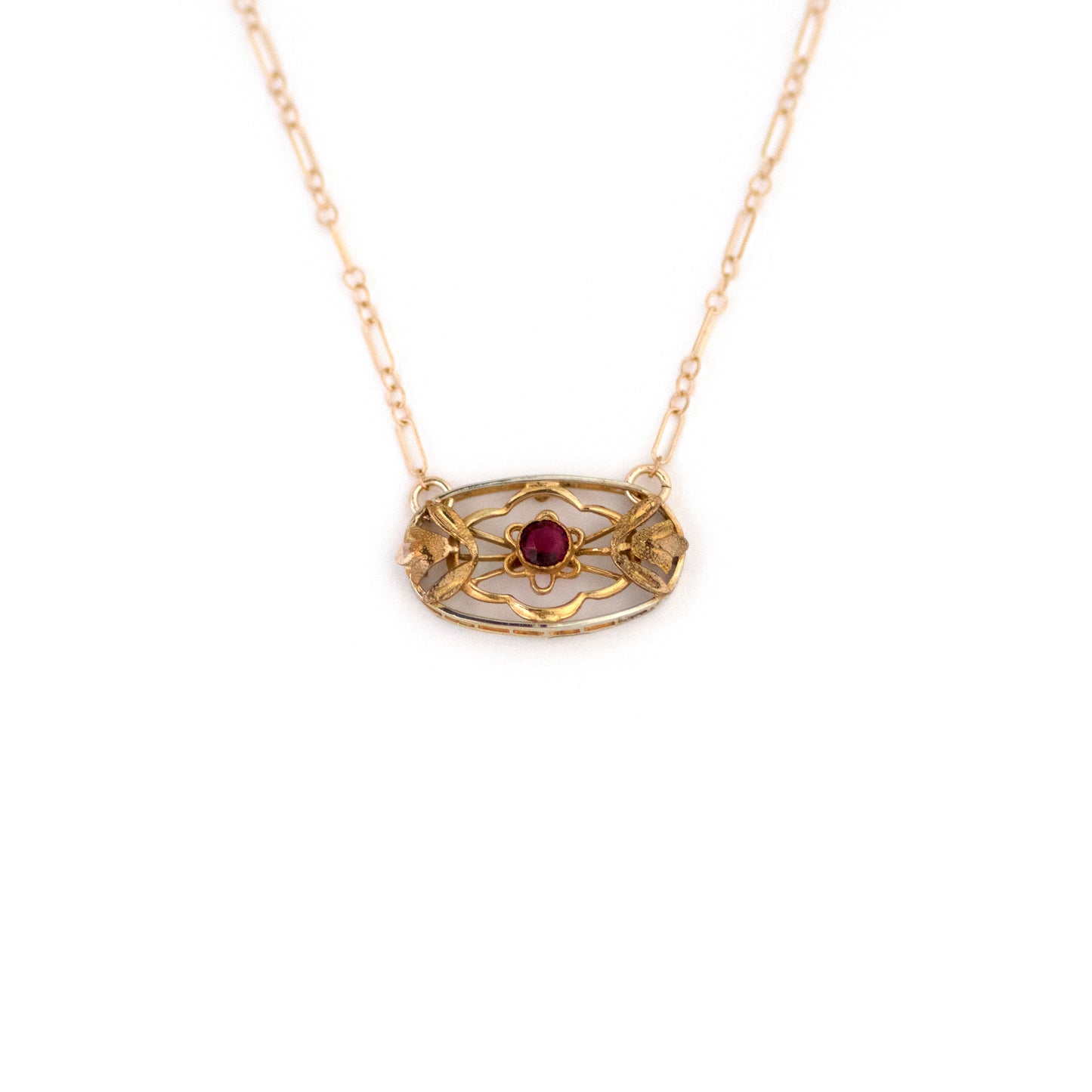 This one-of-a-kind conversion necklace is made up of: Gold filled Victorian brooch pendant from the late 1800s with hand tooled floral tulip details and a ruby red paste stone in its center.