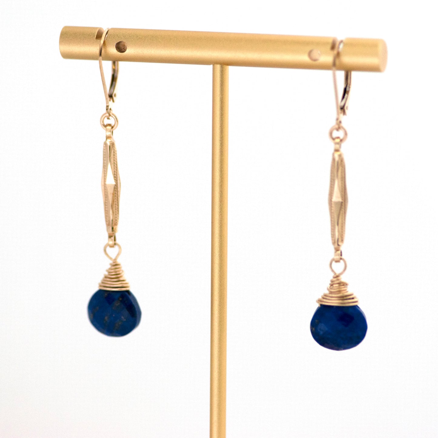 These one-of-a-kind conversion earrings are made up of: Gold filled antique Edwardian watch chain links from the early 1900s with hand tooled details. Lapis lazuli. Earrings hanging from T bar earring stand.