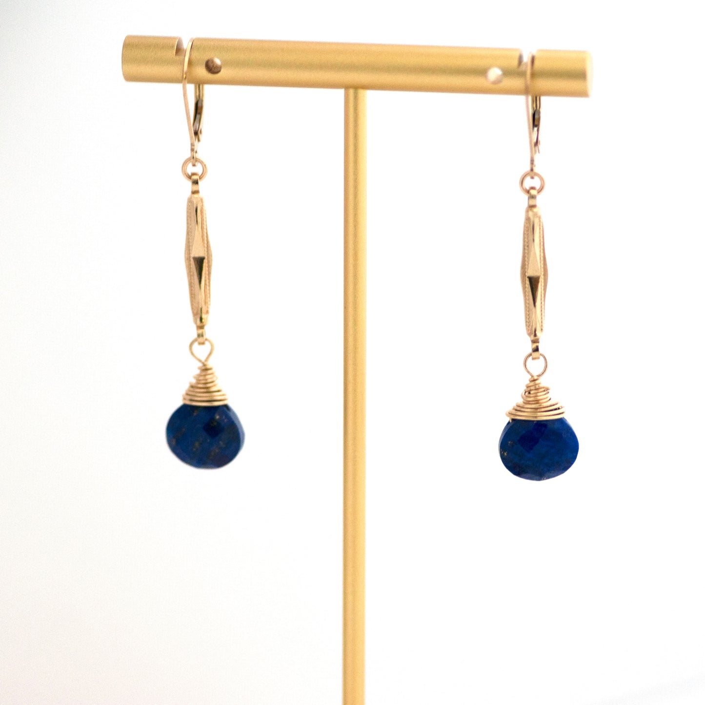 These one-of-a-kind conversion earrings are made up of: Gold filled antique Edwardian watch chain links from the early 1900s with hand tooled details. Lapis lazuli. Earrings hanging from T bar earring stand.