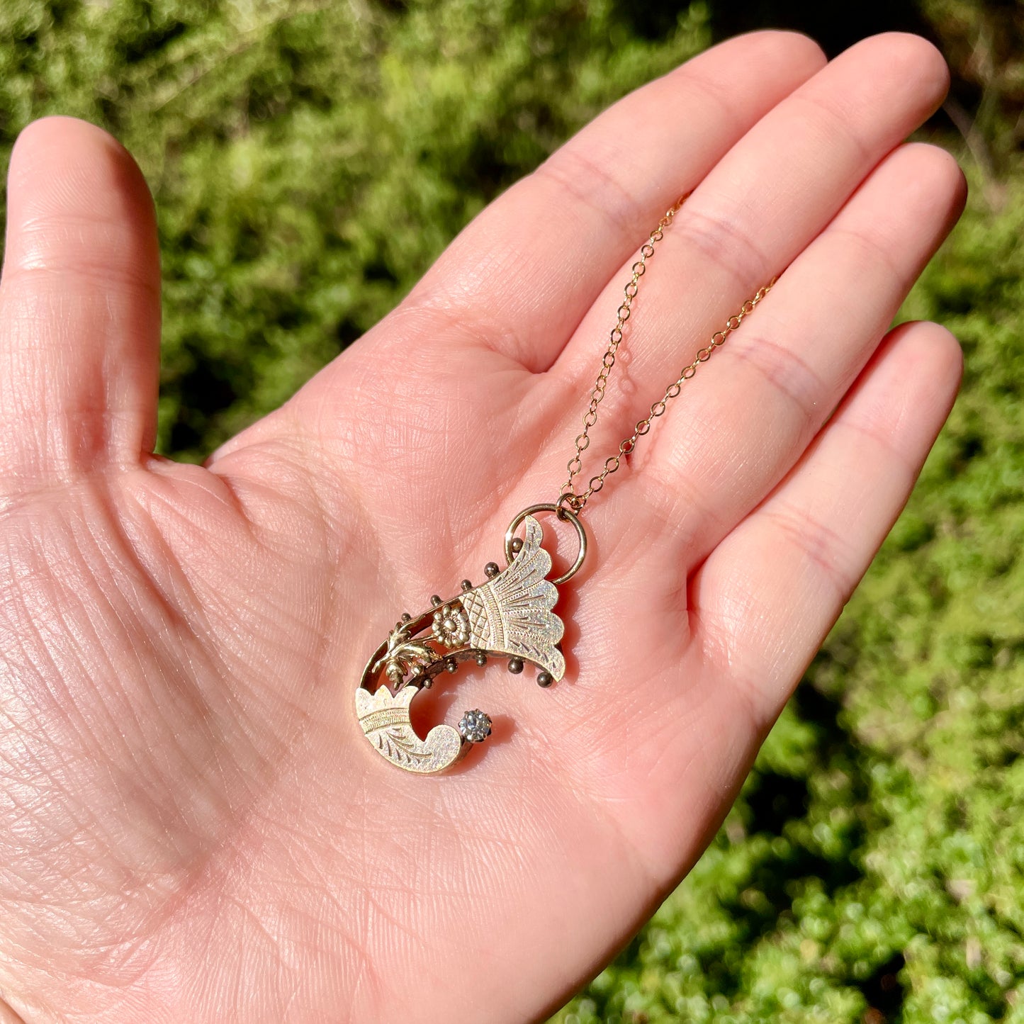 Antique Gold Filled Horn of Plenty Cornucopia Necklace held in hand in the sunlight