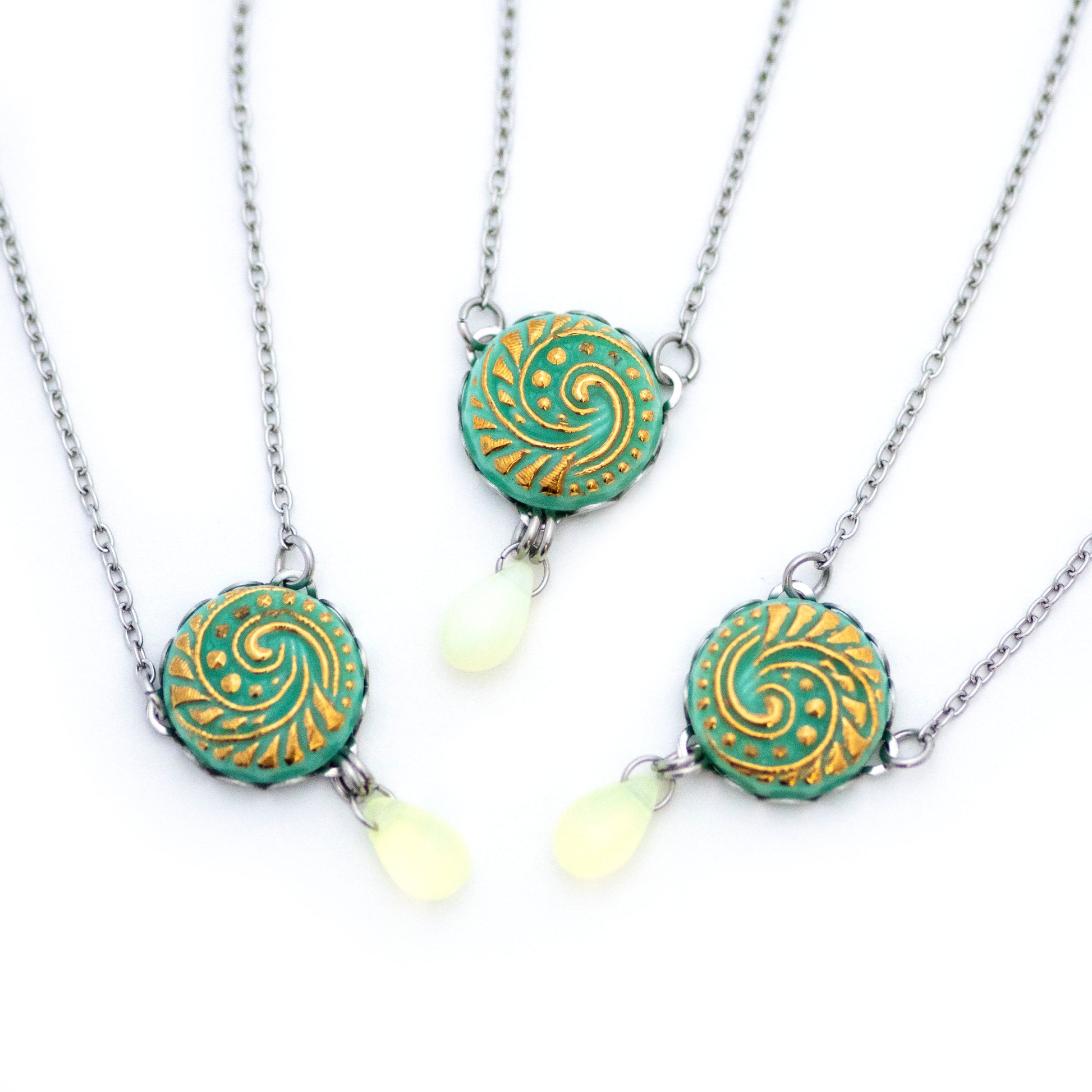 Three button pendant necklaces. Uranium glass button in light turquoise color.  Uranium glass button contains 2% uranium dioxide. This small amount in the glass allows it to fluoresce (glow) green under a black light and is also safe to wear.