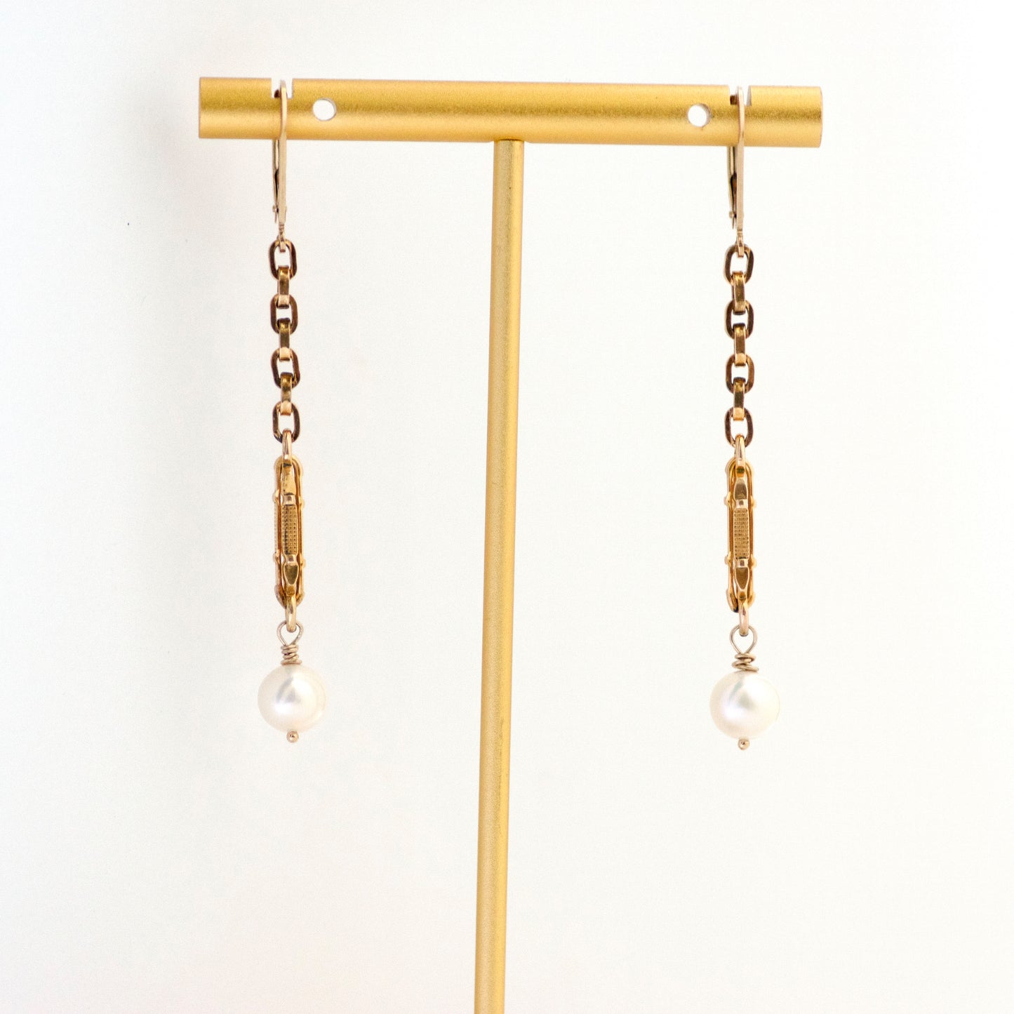 Long Dangling Pearl Drop Antique Watch Chain Earrings hanging on gold tone earring T stand.