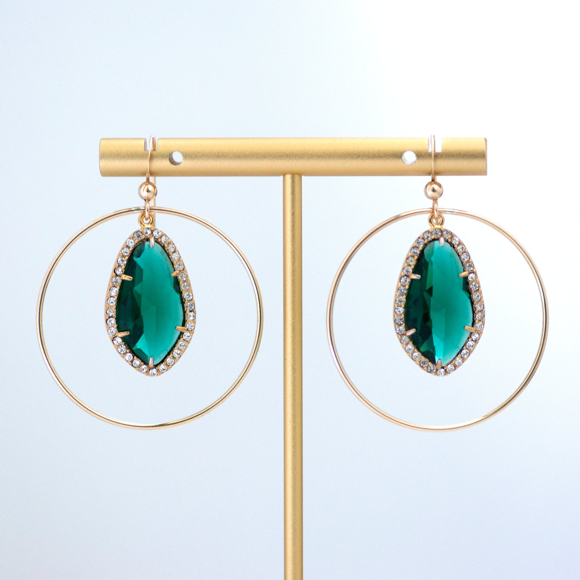These upcycled vintage earrings are made up of:  Gold tone vintage emerald green crystal rhinestone drops and 14k gold fill. Earrings are hanging on a gold tone T bar earrings stand.