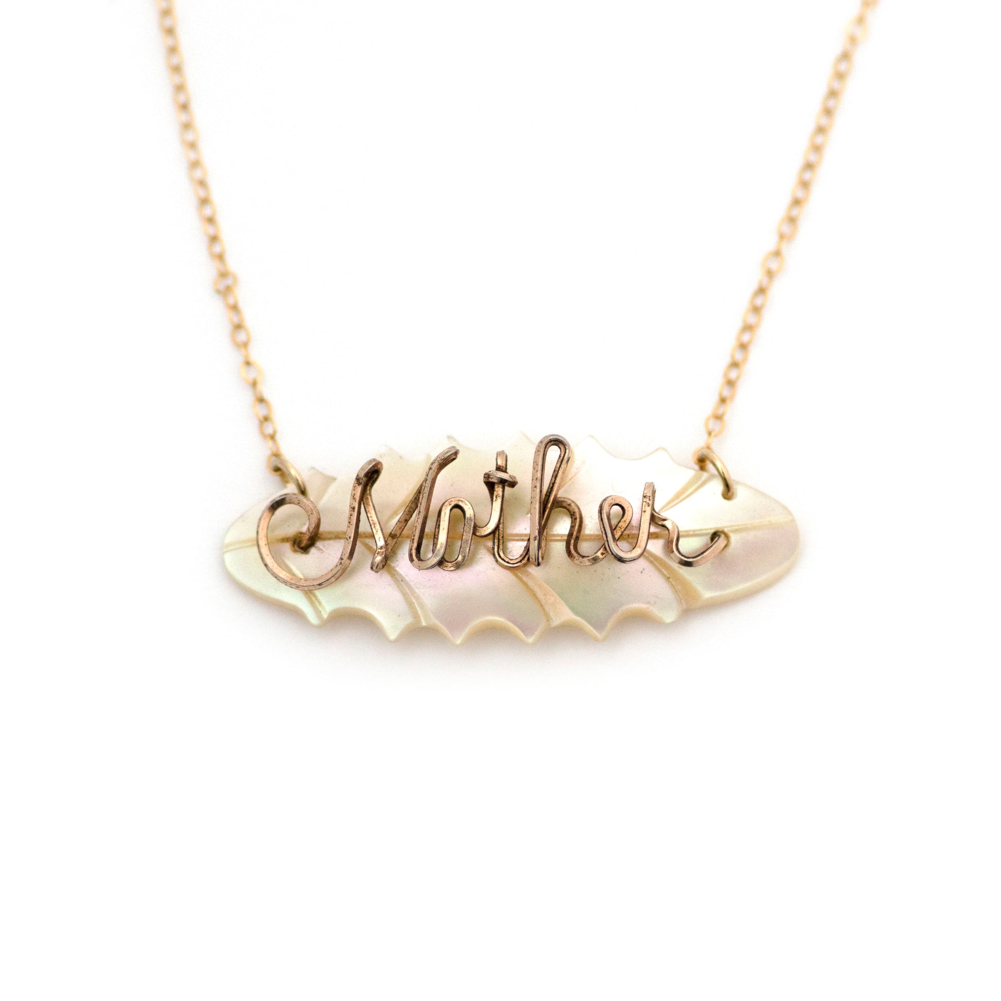 mid century from the 1960s leaf shape mother of pearl pendant with gold filled wire script spelling "Mother" brooch conversion necklace. Pendant is on a split gold filled chain. Necklace is on an all white background.