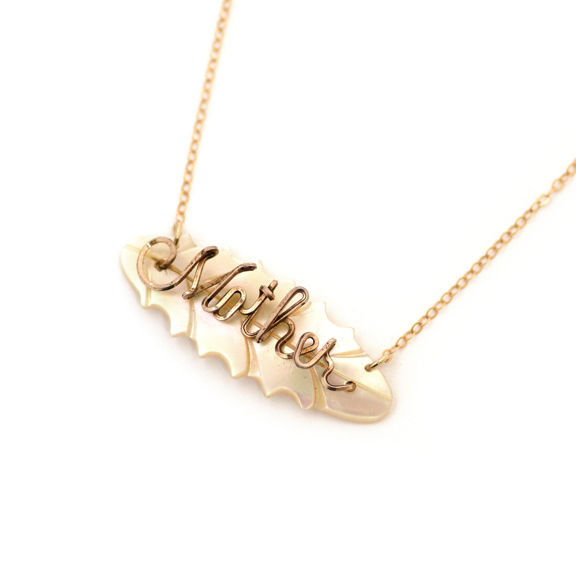 "Mother" gold filled wire script on leaf shaped mother of pearl brooch conversion pendant necklace on gold filled chain. Pendant necklace is on an all white background.