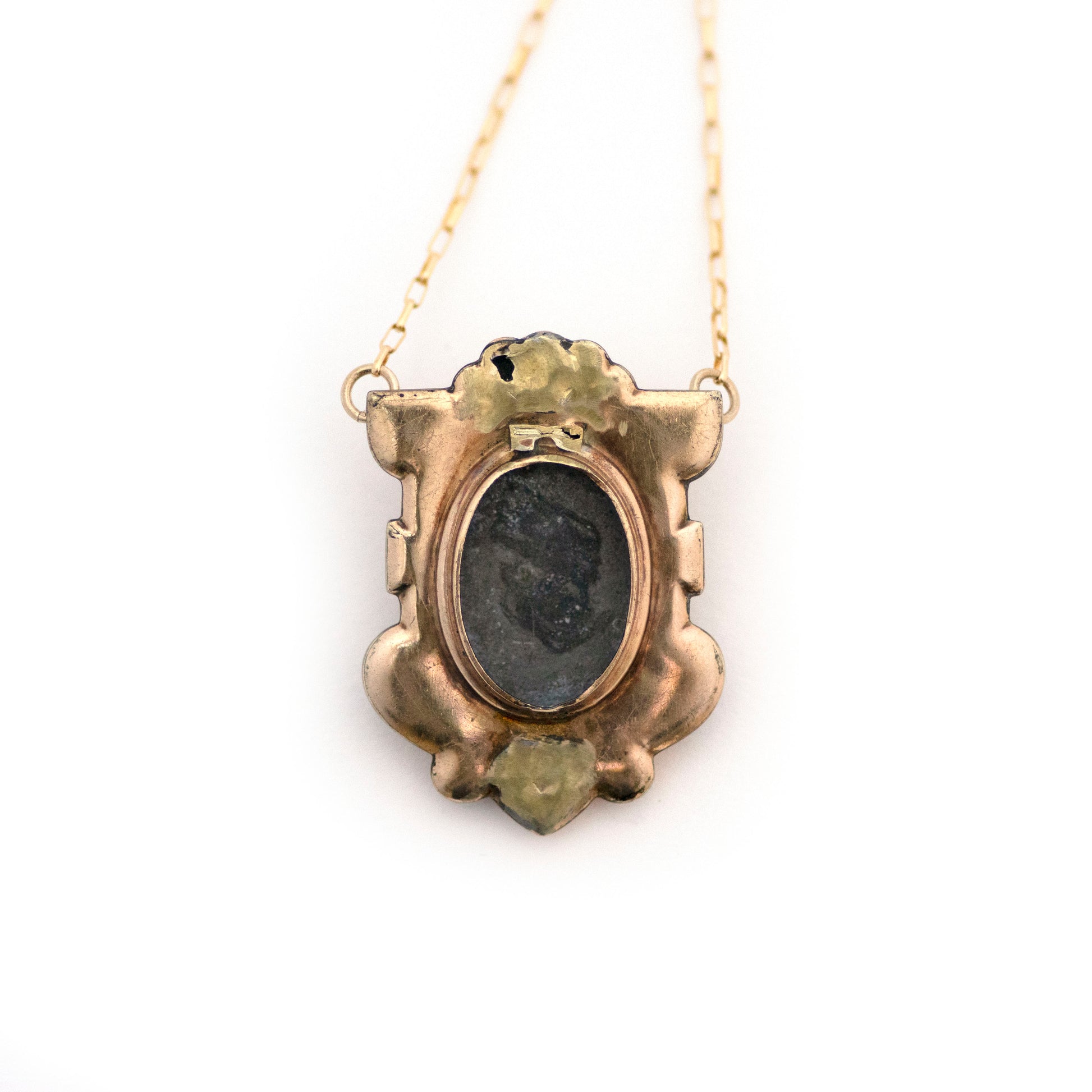 The back of Antique Victorian Blue Paste Shield Necklace shows a hidden locket on the back where the glass cover is missing.