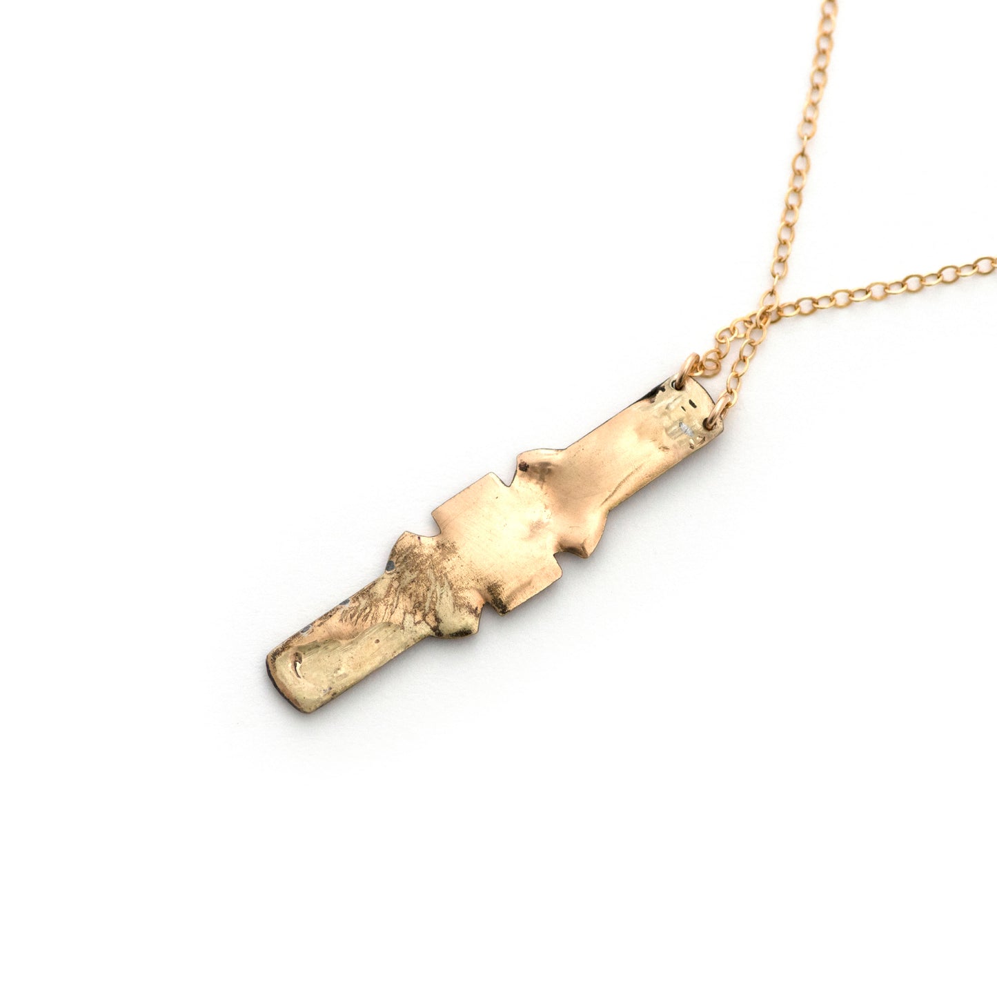 The back of an antique vertical bar pin conversion pendant necklace on an all white background.
