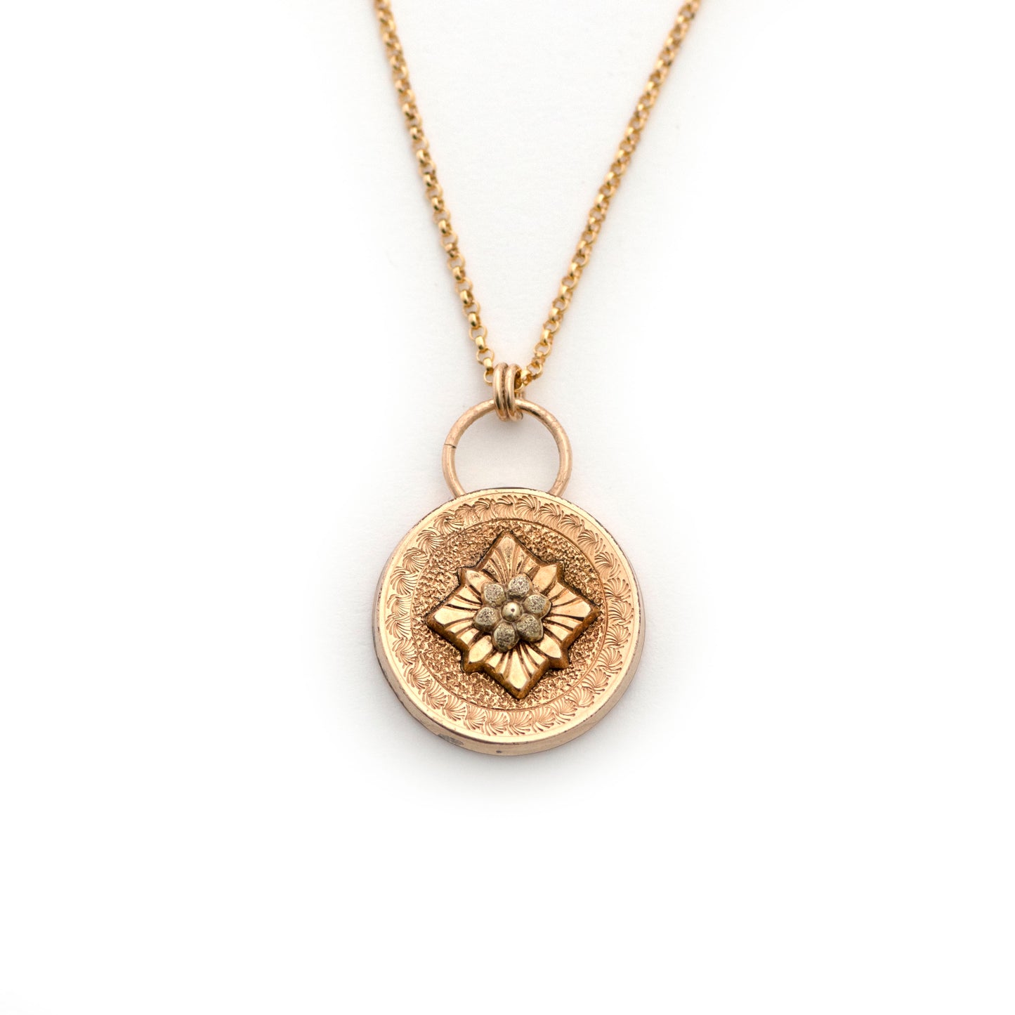 An antique cufflink conversion pendant resembling a door knocker shape that is strung on a 14k gold filled chain and laying on an all white background.
