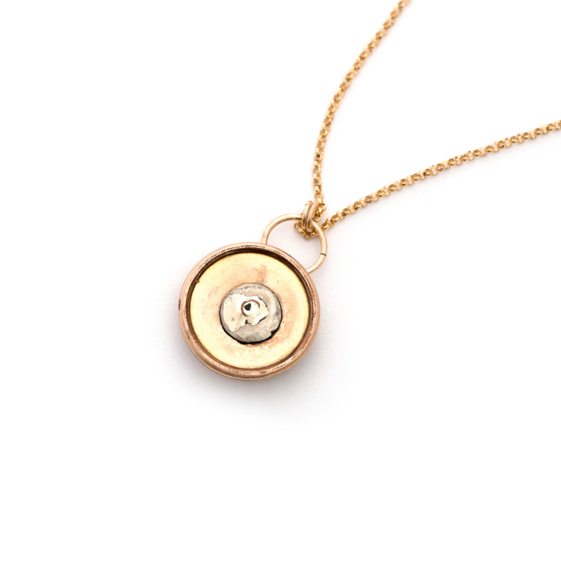The back of an antique cufflink conversion pendant resembling a door knocker shape that is strung on a 14k gold filled chain and laying on an all white background.