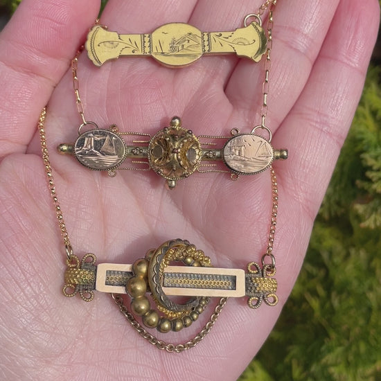 video of three antique Victorian bar pin necklaces in the palm of a hand