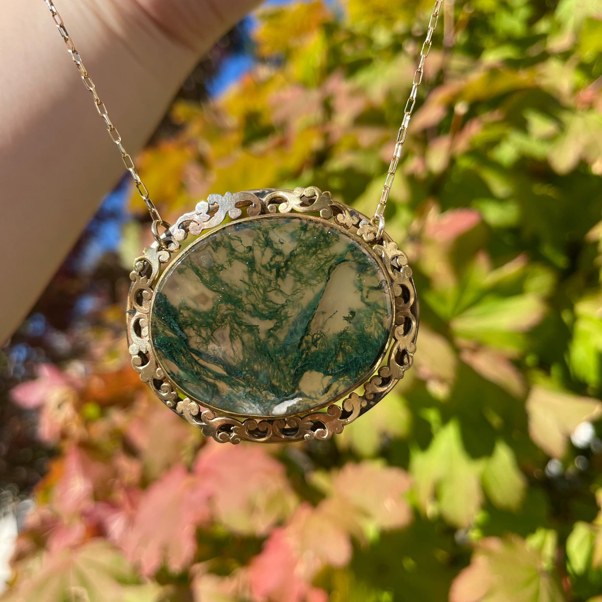 Antique Victorian Crystal Quartz Moss Green Agate Necklace held in the outdoor sunlight