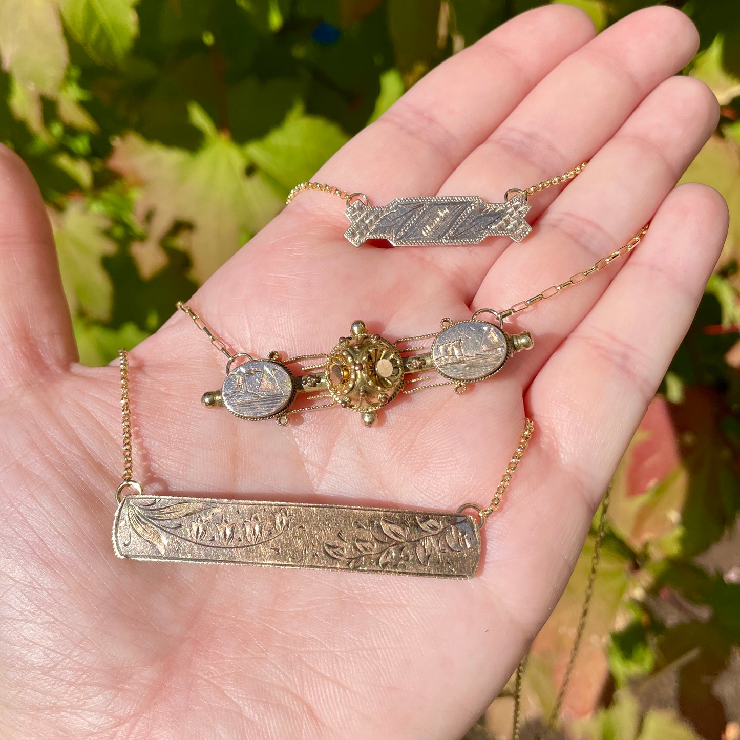 three antique victorian bar pin necklaces held in palm of hand